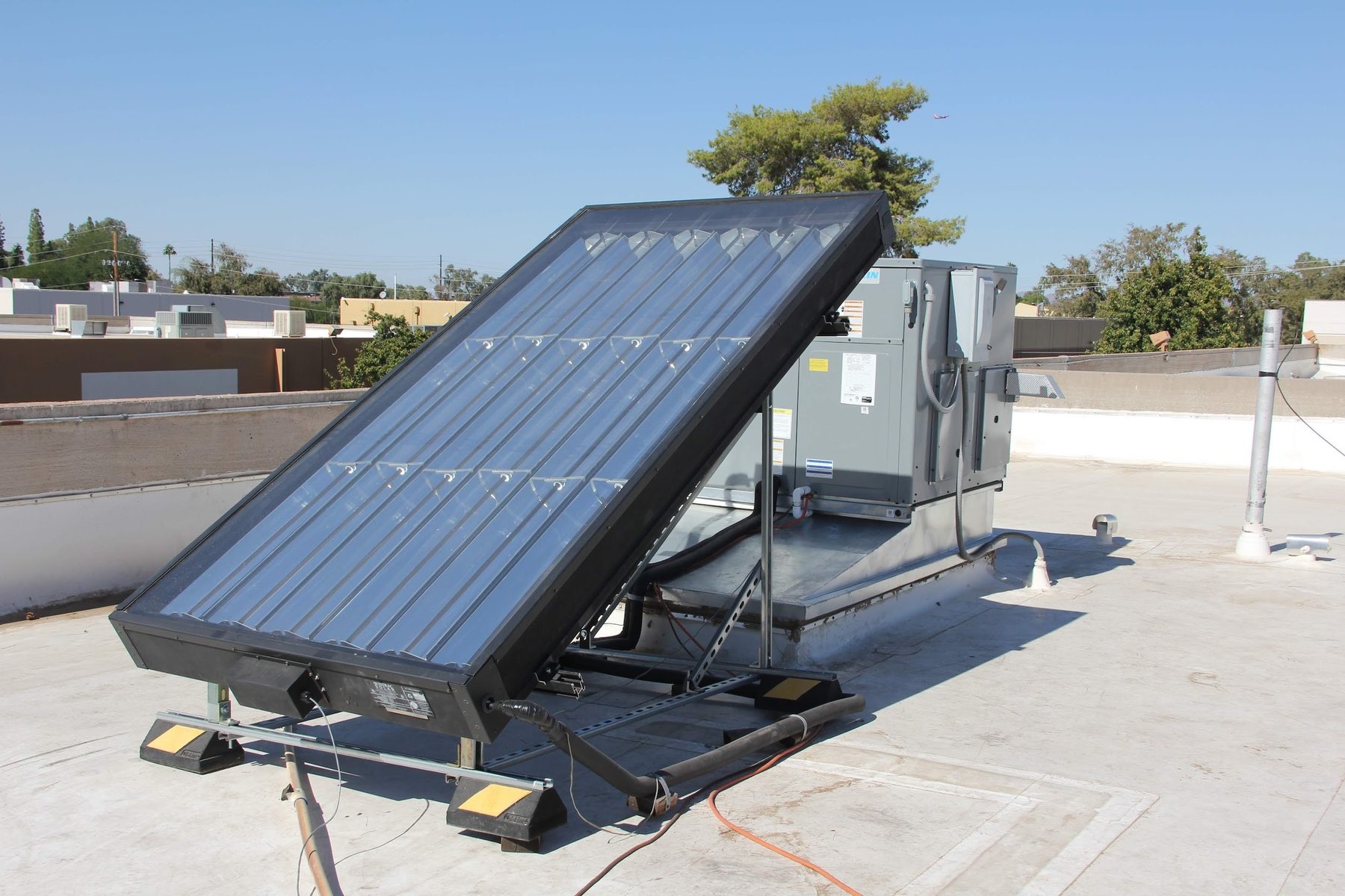 Sun-tracking IESS panel installed next to an HVAC outdoor unit on a commercial rooftop